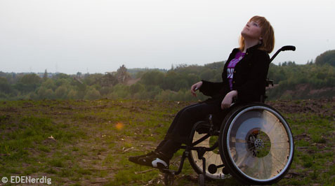 Junge Frau im Rollstuhl unterwegs auf einem Feldweg