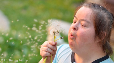 Frau mit Down Syndrom und Pusteblume